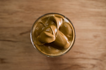 Iced Dalgona Coffee, a trendy korean style  cremy whipped coffee on fresh milk, on wooden background. Top view