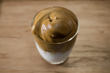 Iced Dalgona Coffee, a trendy korean style  cremy whipped coffee on fresh milk, on wooden background