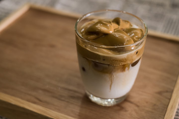 Iced Dalgona Coffee, a trendy korean style  cremy whipped coffee on fresh milk, on wooden tray on the table
