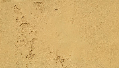 Close-up of a weathered and old concrete wall, yellow paint is peeling off. High resolution abstract full frame textured background.