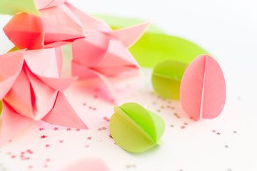 Handmade paper green and pink eggs, origami tulips against of silver stars on white. Happy Easter background. DIY concept.