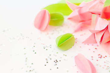 Handmade paper green and pink eggs, origami tulips against of silver stars on white. Happy Easter background. DIY concept. Copy space.