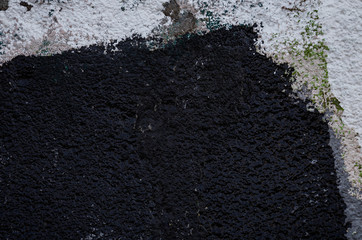 Close-up of a plastered and rough wall painted in white and black. High resolution full frame textured background.