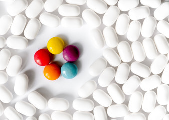 White and bright multi-colored pills on bright white background. The concept of individuality, out the box, non-standard thinking. Personality concept,medical concept, antibiotics.copy space.