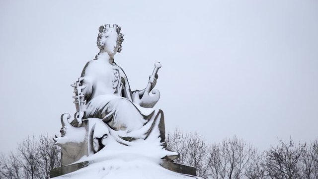 Statue of a woman covered with snow near the Eiffel Tower in winter with snow in Paris France, seen from below, on a snowy day