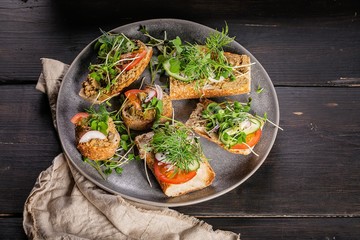 Traditional Mediterranean cuisine. Bruschettas and canapes with turkey pate, tomatoes, cucumbers and microgreens. Delicious homemade breakfast or snack