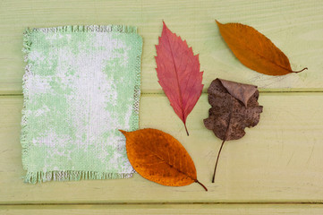 Fototapeta na wymiar .A canvas napkin and tree leaves lying on a wooden surface. Background for fall and natural objects.
