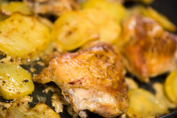 Close-up of delicious baked potatoes and poultry, some objects out of focus. Home cooking