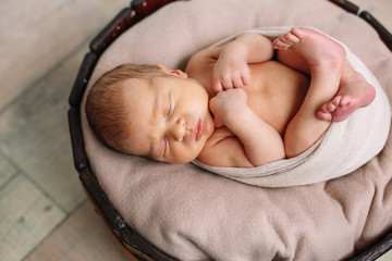 
Newborn baby boy, in the photo the baby is 7 days old from birth, wrapped in a wrapping, sleeps sweetly in a basket