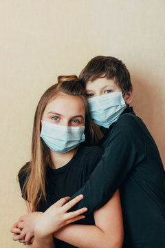 Caucasian Teenagers Brother And Sister In A Face Mask Hug And Lovingly Support Each Other During Difficult Times During Self-isolation In Quarantine Due To The Outbreak Of The Coronavirus Epidemic.