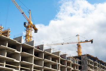 Tower building cranes and working builders on building multi-storey house