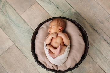 
Newborn baby boy, in the photo the baby is 7 days old from birth, wrapped in a wrapping, sleeps sweetly in a basket
