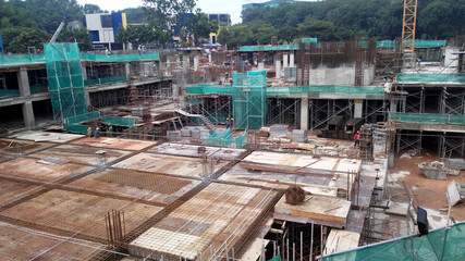 The construction site is operating during the day. Workers are busy carrying out their activities as planned under the supervisor's supervision.