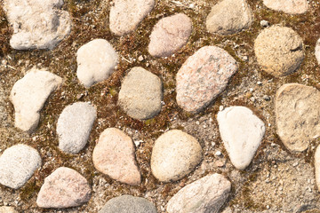 Cobbled surface with paving stones in different shades - top view.Natural stone pavement. Exterior floor covering.