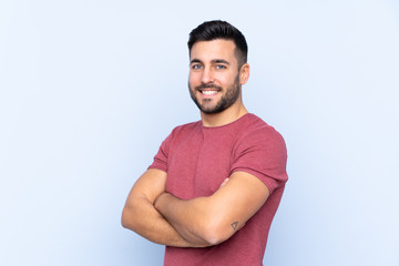 Obraz premium Young handsome man with beard over isolated blue background with arms crossed and looking forward