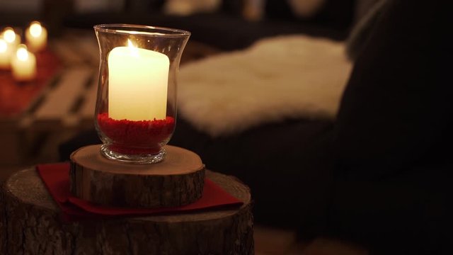 Romantic mood environmental wax candle flame in a glass panning right
