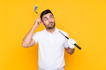 Golfer player man over isolated yellow background having doubts and with confuse face expression