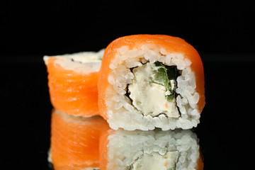 Delicious sushi rolls on black mirror background. Japanese food