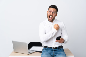 Young businessman holding a mobile phone celebrating a victory