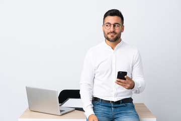Young businessman holding a mobile phone standing and looking to the side