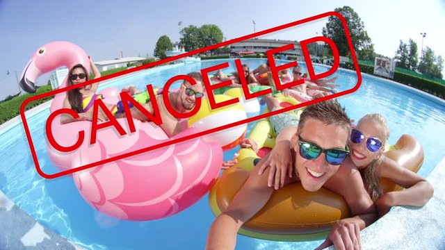 SLOW MOTION, CLOSE UP: Big red cancelled sign covers the smiling faces of happy tourists partying at a pool on a sunny summer day. Friends will have to cancel their vacation because of covid-19 virus