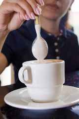 Mujer con una cuchara revolviendo café capuchino / Woman with a spoon stirring cappuccino coffee