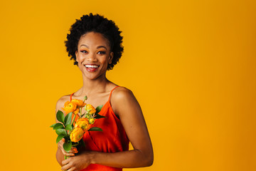 Portrait of a happy smiling young woman in orange with  yellow peony flowers bouquet