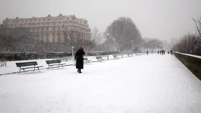 People with umbrellas walking in the snow near the Eiffel Tower in Paris France in winter on a Christmas snowy day
