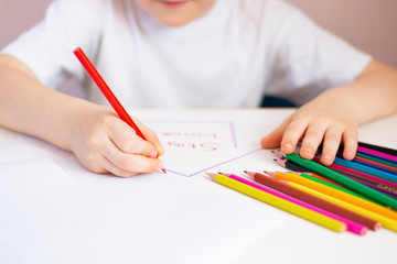 Children's hand holds a colored pencil. Homework preschooler.