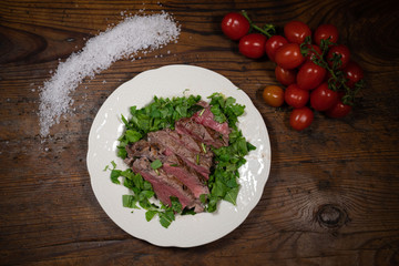 grilled sirloin steak with fresh rocket with coarse salt and salad tomatoes from the table of an old tavern