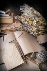 Open unwritten letter and envelope, glasses, books and a dried bouquet of flowers. Vintage style,...