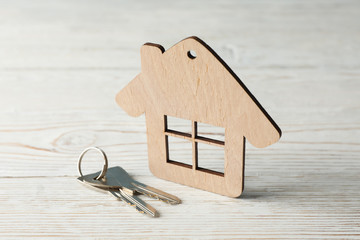 Wood house and keys on wooden background, close up