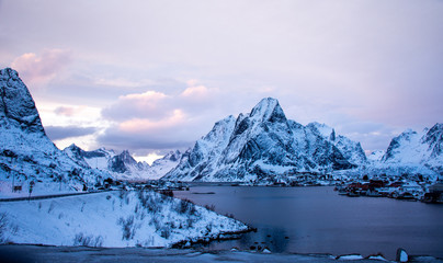 Fototapeta na wymiar view of the snowy mountains and the sea in winter as night falls in Reine, Lofoten