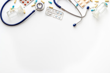 Flu treatment concept with pills and stethoscope on white table top view copy space