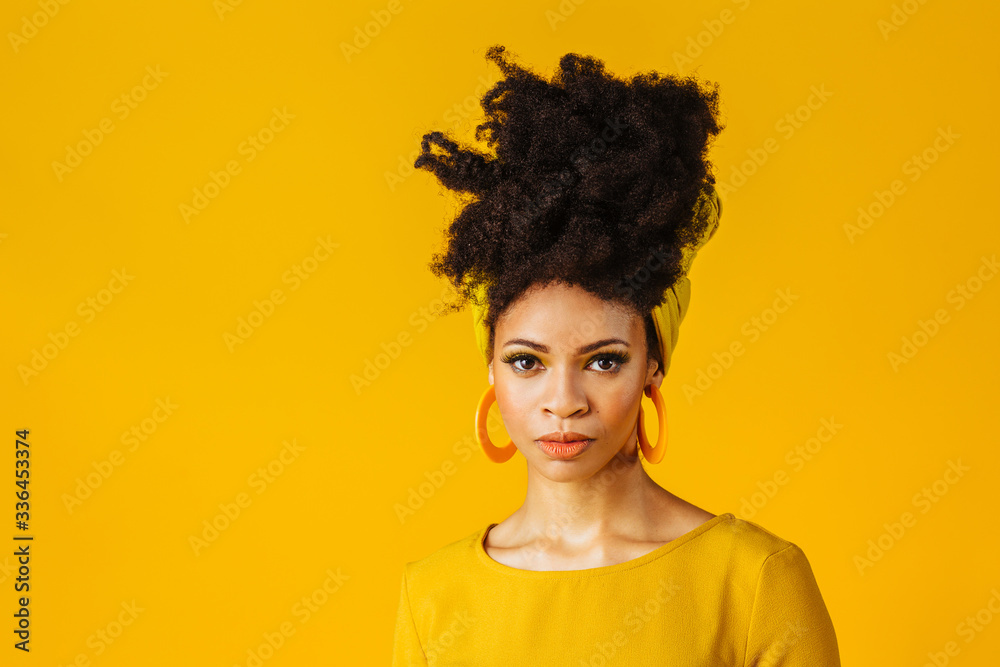 Wall mural portrait of a serious young woman with big yellow hoop earrings and hair wrapped with african head w