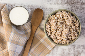 Top view of crushed barley in bowl and kefir in glass on the white background