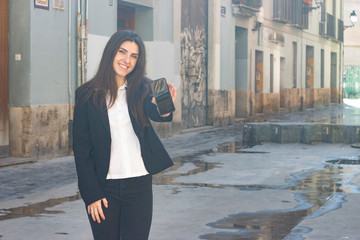 Portrait of pretty bussiness woman model holding and showing mobile phone, in the city, white shirt...