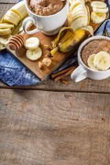 Portioned Banana bread mugcake in small mugs. Easy sweet baking idea, With fresh bananas, nuts, honey and spices on rustic wooden background copy space