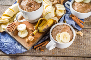 Portioned Banana bread mugcake in small mugs. Easy sweet baking idea, With fresh bananas, nuts, honey and spices on rustic wooden background copy space