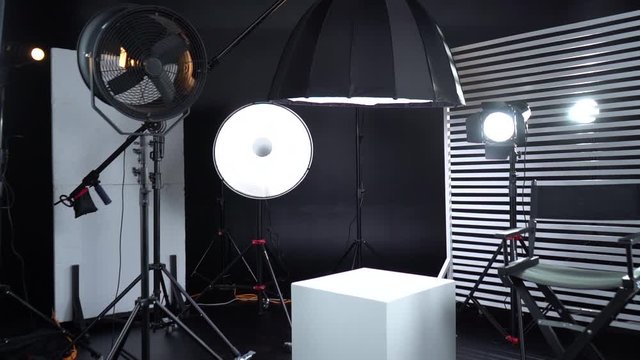 Dark room cyclorama. Modern photo studio with professional equipment. Empty photo studio with lighting equipment. Interior of modern photo studio with director production chair.