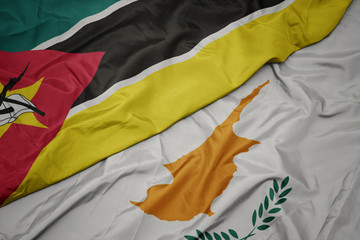 waving colorful flag of cyprus and national flag of mozambique.