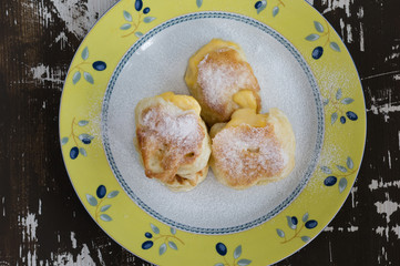 Top view of fried fritters sifted by sugar powder on plate on the wooden background