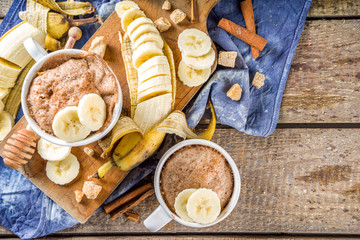 Portioned Banana bread mugcake in small mugs. Easy sweet baking idea, With fresh bananas, nuts, honey and spices on rustic wooden background copy space