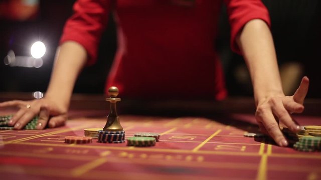 Game table in the casino. The carpet is red , the dealer's hand. Bets on the chips . People playing roulette