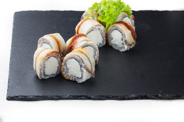 .maki sushi with eel and soft cheese on a stone board. on a white background