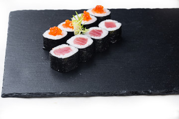 Maki sushi with salmon, red caviar and cream sauce on a stone board. on a white background