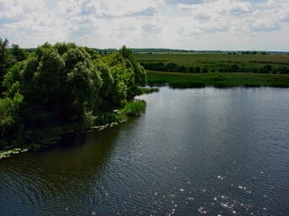 A beautiful river on a summer day in the Kursk region flows through green meadows.