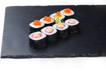 Maki sushi with salmon, red caviar and cream sauce on a stone board. on a white background