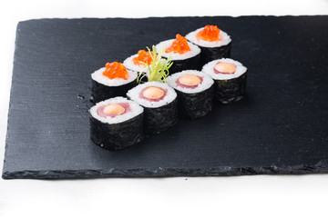 Maki sushi with salmon, red caviar and cream sauce on a stone board. on a white background