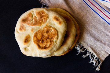 Pita bread on a dark table, top view
